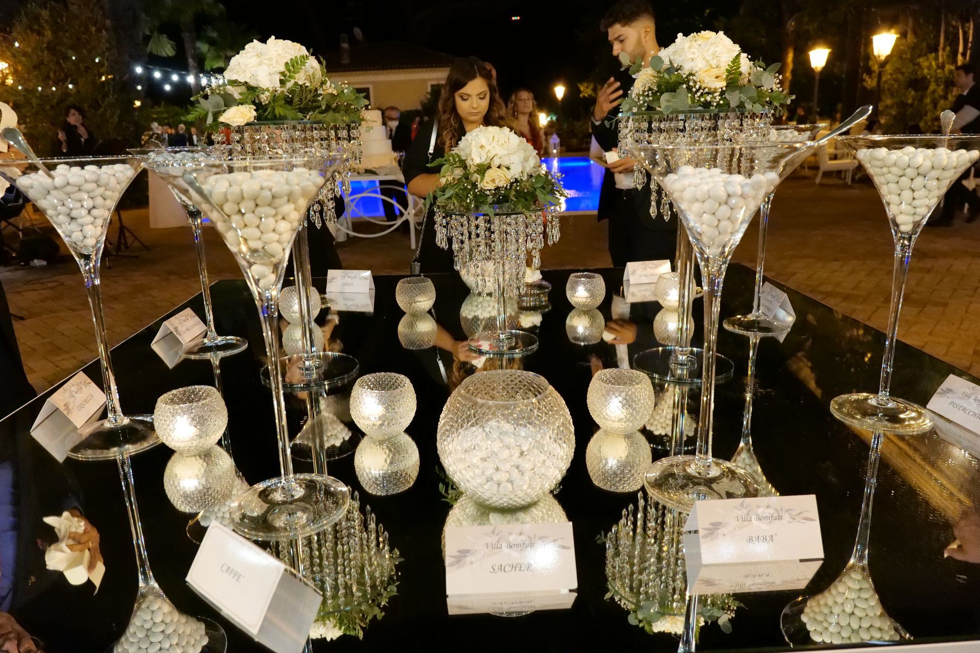 Un tavolo con sopra bicchieri da martini pieni di caramelle e fiori.