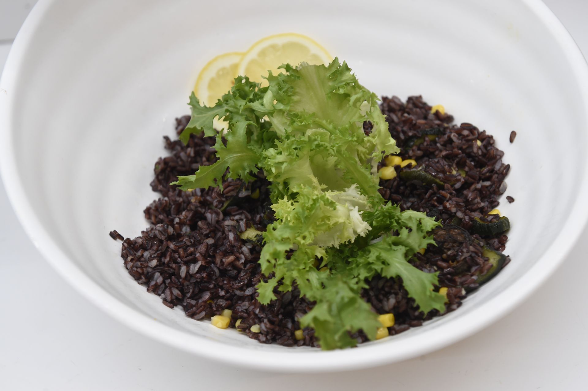Una ciotola bianca piena di riso nero e lattuga