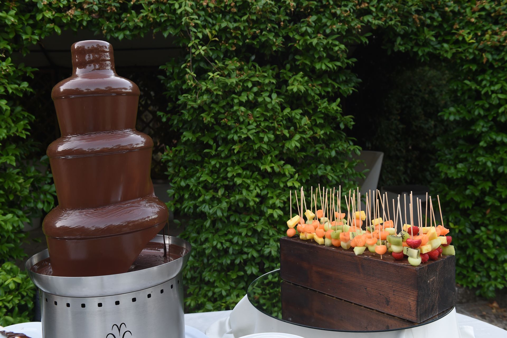 Una fontana di cioccolato e una scatola di frutta su un tavolo