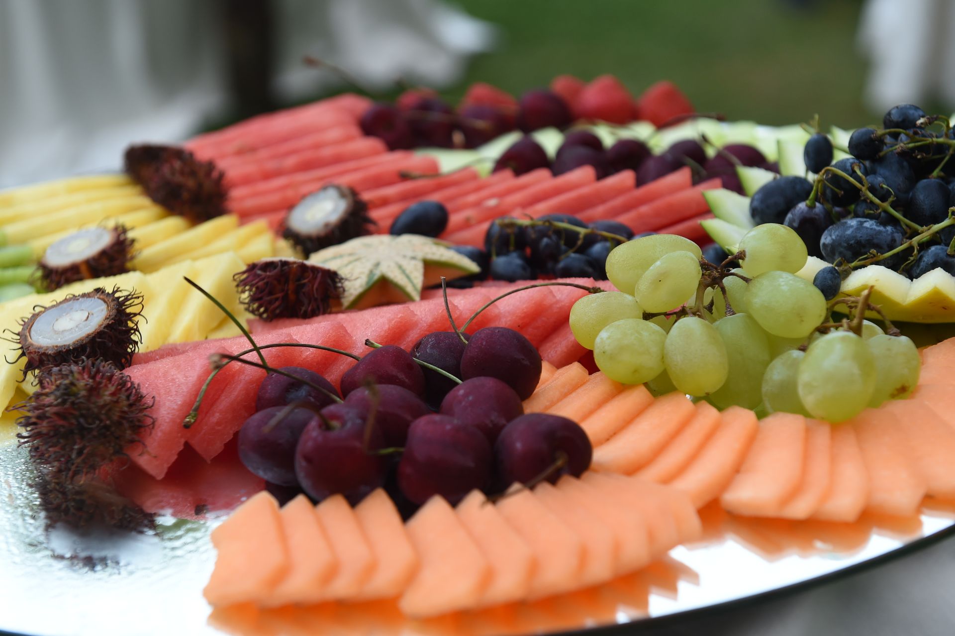 Un vassoio di frutta a fette con uva e anguria