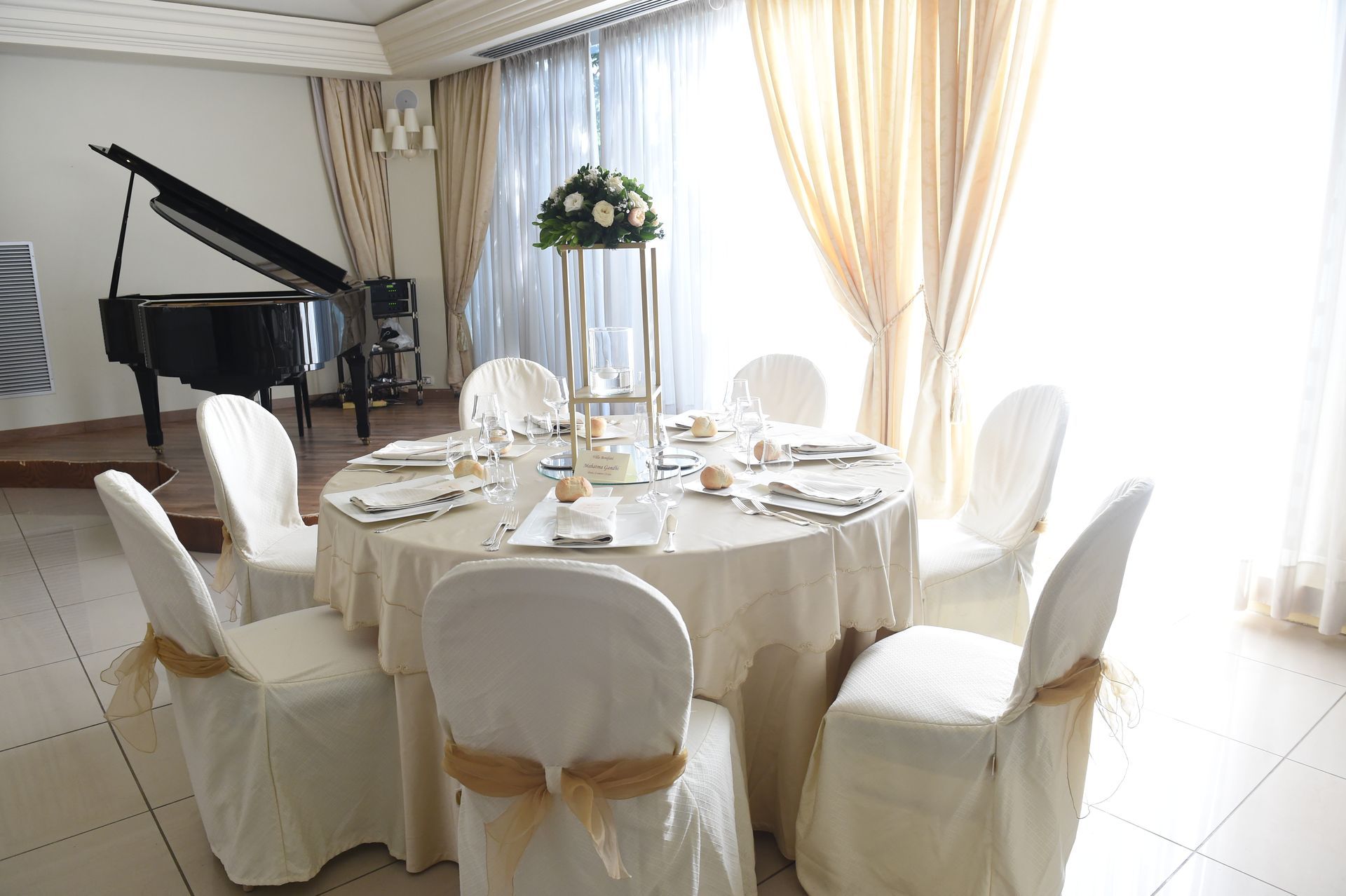 Una stanza con tavolo e sedie e un pianoforte.