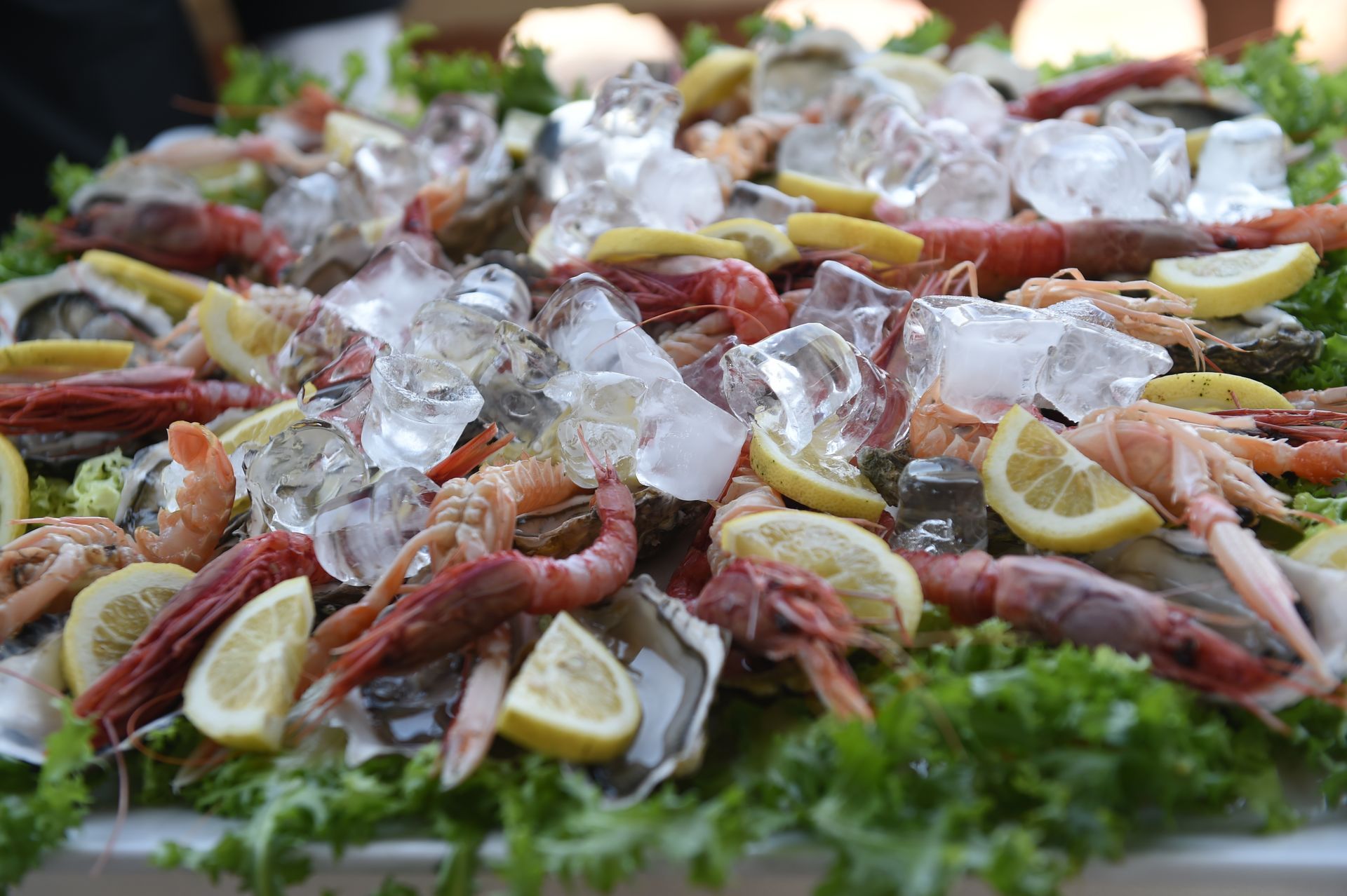 Un piatto di frutti di mare con ghiaccio e fette di limone su un tavolo.
