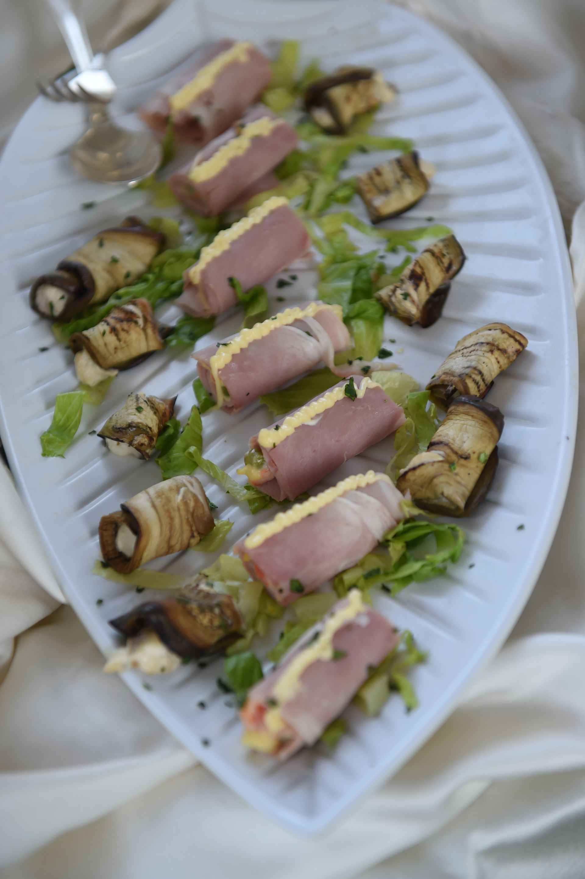 Un piatto bianco condito con una varietà di cibo su un tavolo.