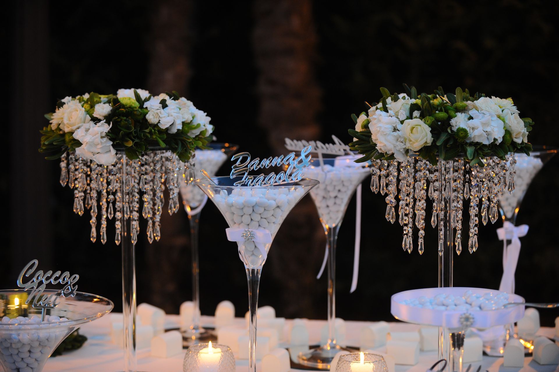 Un tavolo con tre bicchieri da martini pieni di fiori e candele.