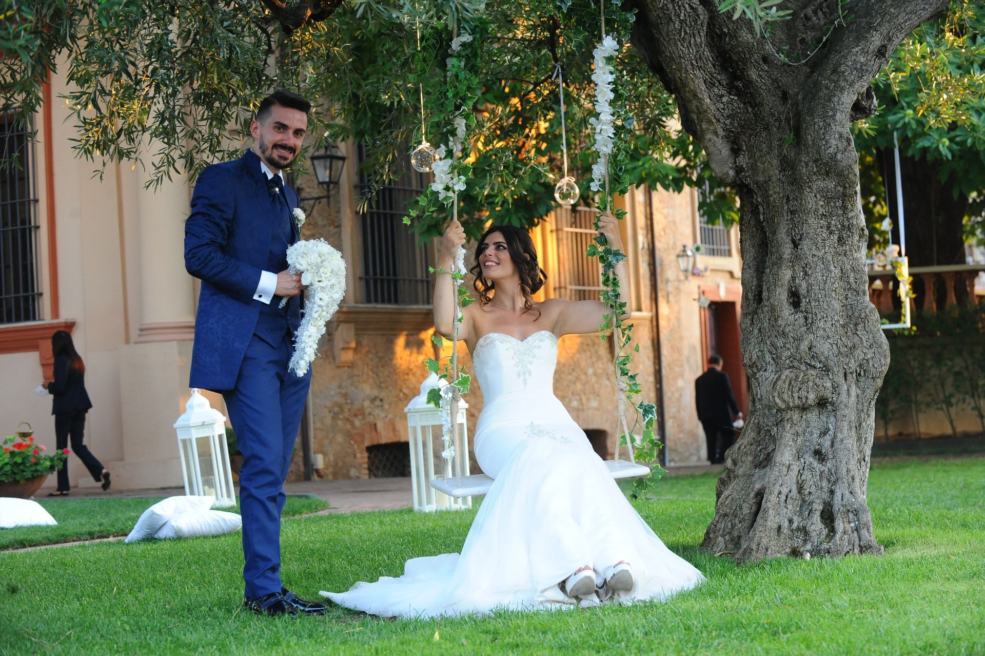 Una sposa e uno sposo posano per una foto mentre la sposa è seduta su un'altalena.