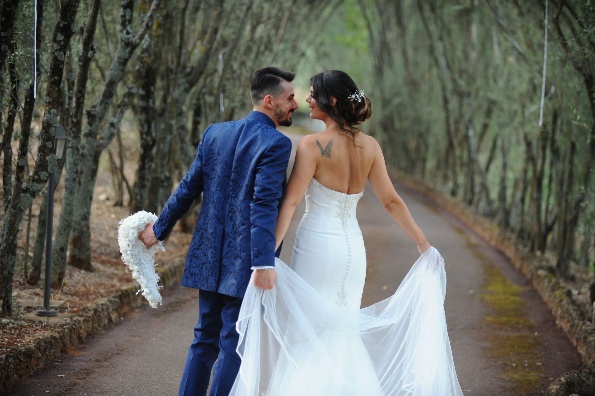 Una sposa e uno sposo stanno camminando lungo un sentiero nel bosco.