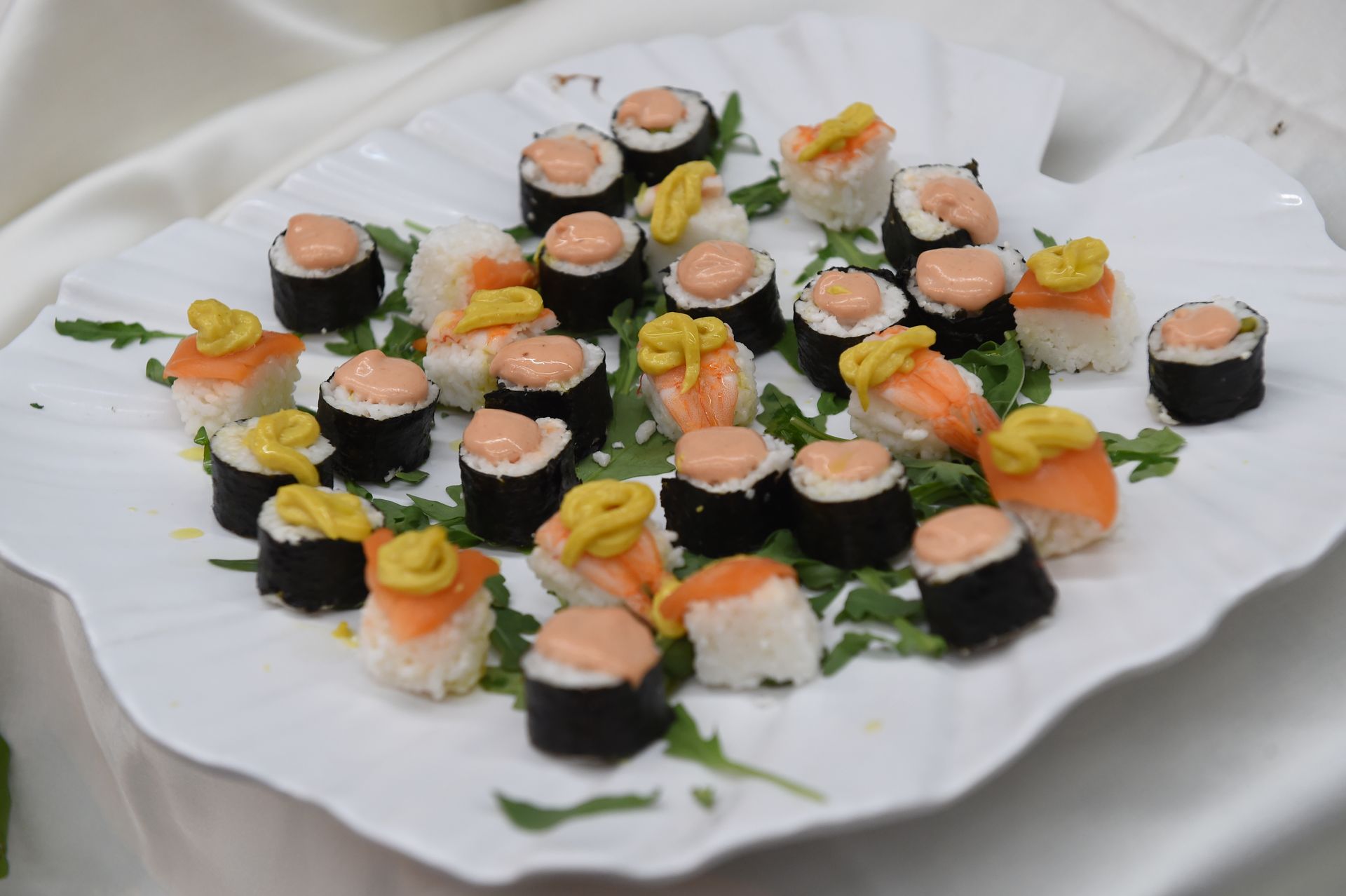 Un piatto bianco condito con involtini di sushi e senape