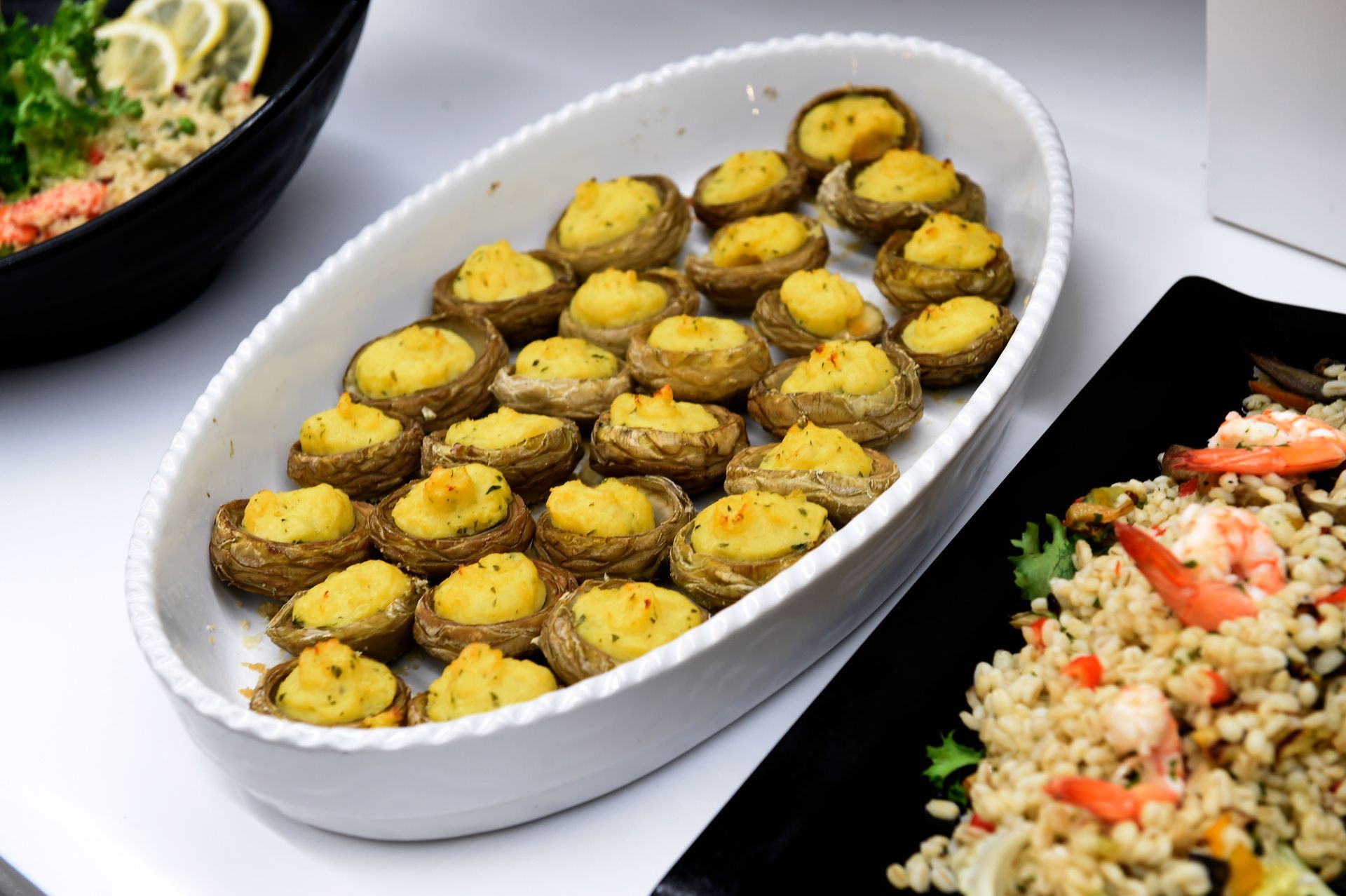 Un piatto ovale bianco pieno di funghi ripieni su un tavolo.