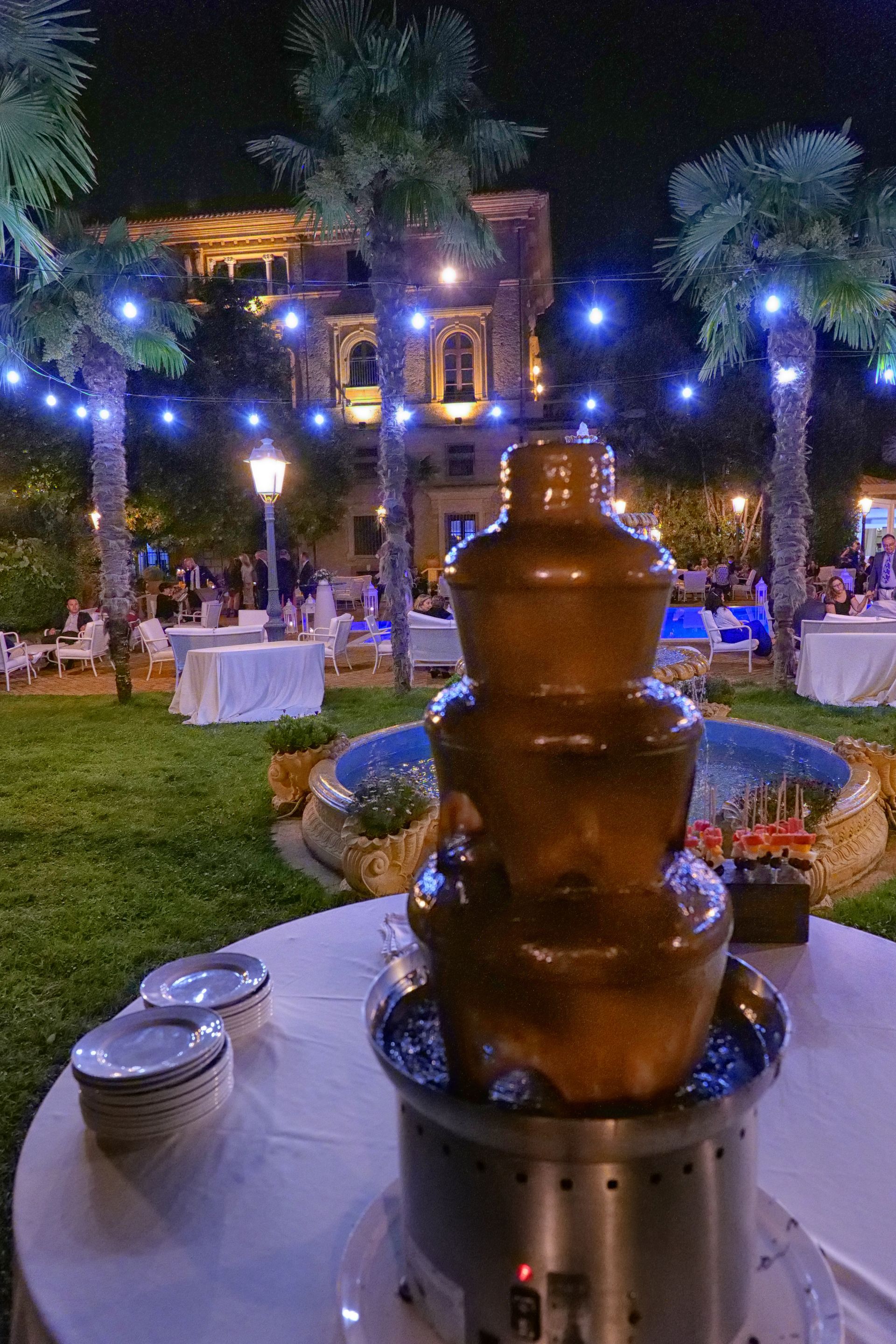 Una fontana di cioccolato è seduta su un tavolo fuori di notte.