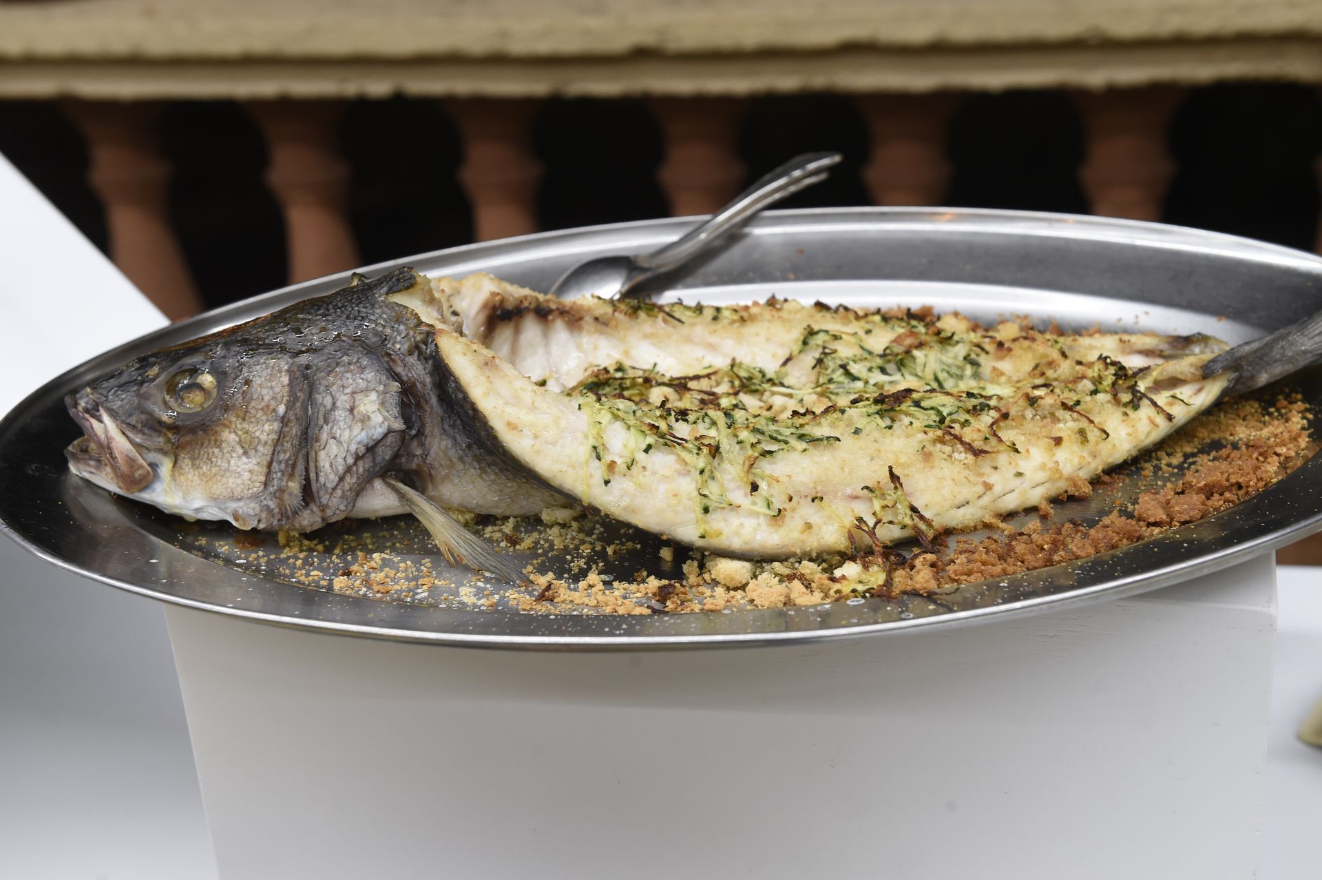 Un pesce è seduto sopra una piastra di metallo su un tavolo.