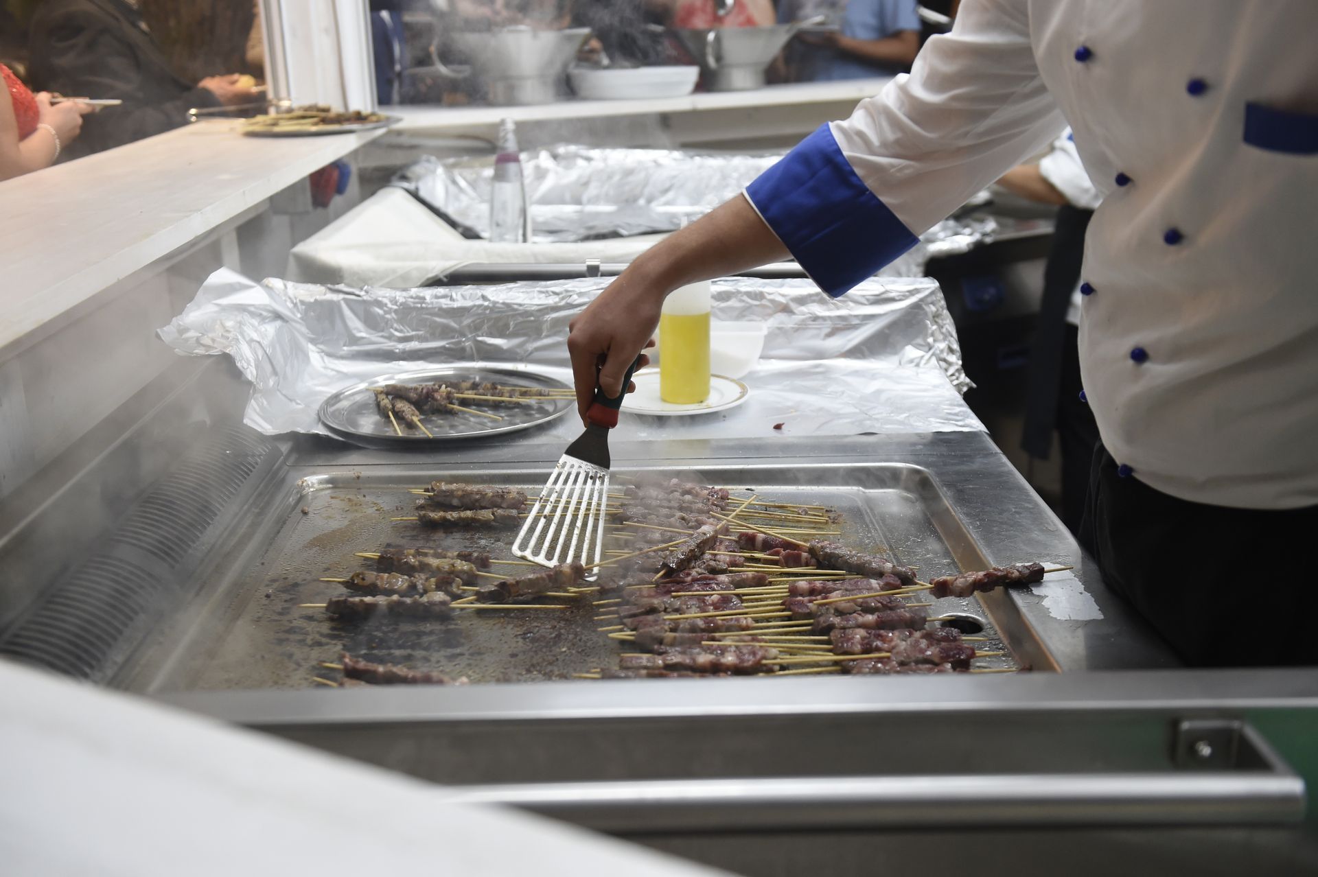 Uno chef cucina la carne sulla griglia con una spatola.