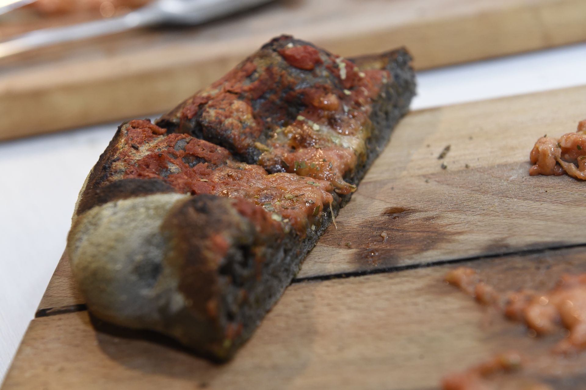 Una fetta di pizza è seduta su un tagliere di legno.