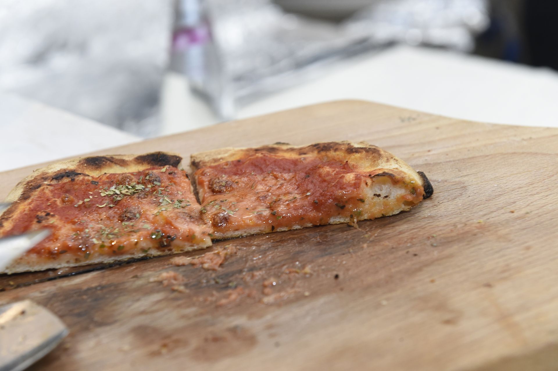 Una fetta di pizza viene tagliata su un tagliere di legno.