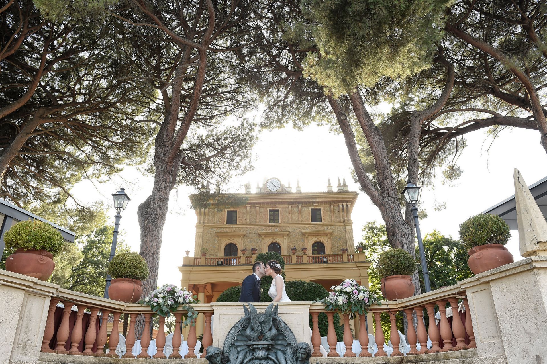 Una sposa e uno sposo si baciano davanti a un grande edificio.