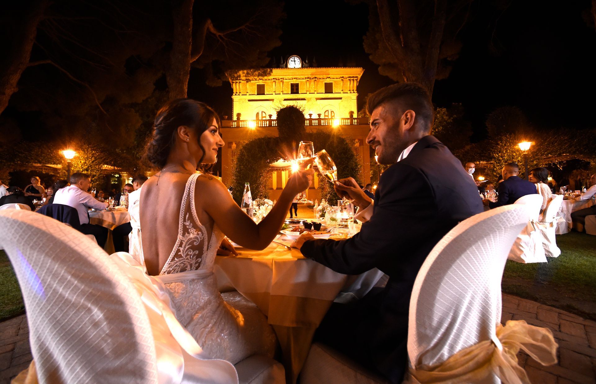 Gli sposi sono seduti a un tavolo e brindano con champagne.