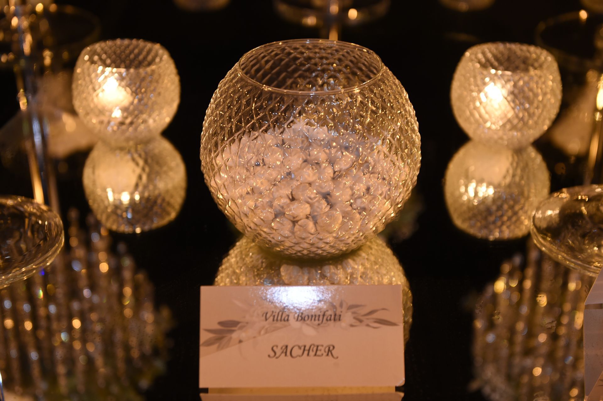 Su un tavolo è seduta una ciotola di vetro piena di caramelle bianche.