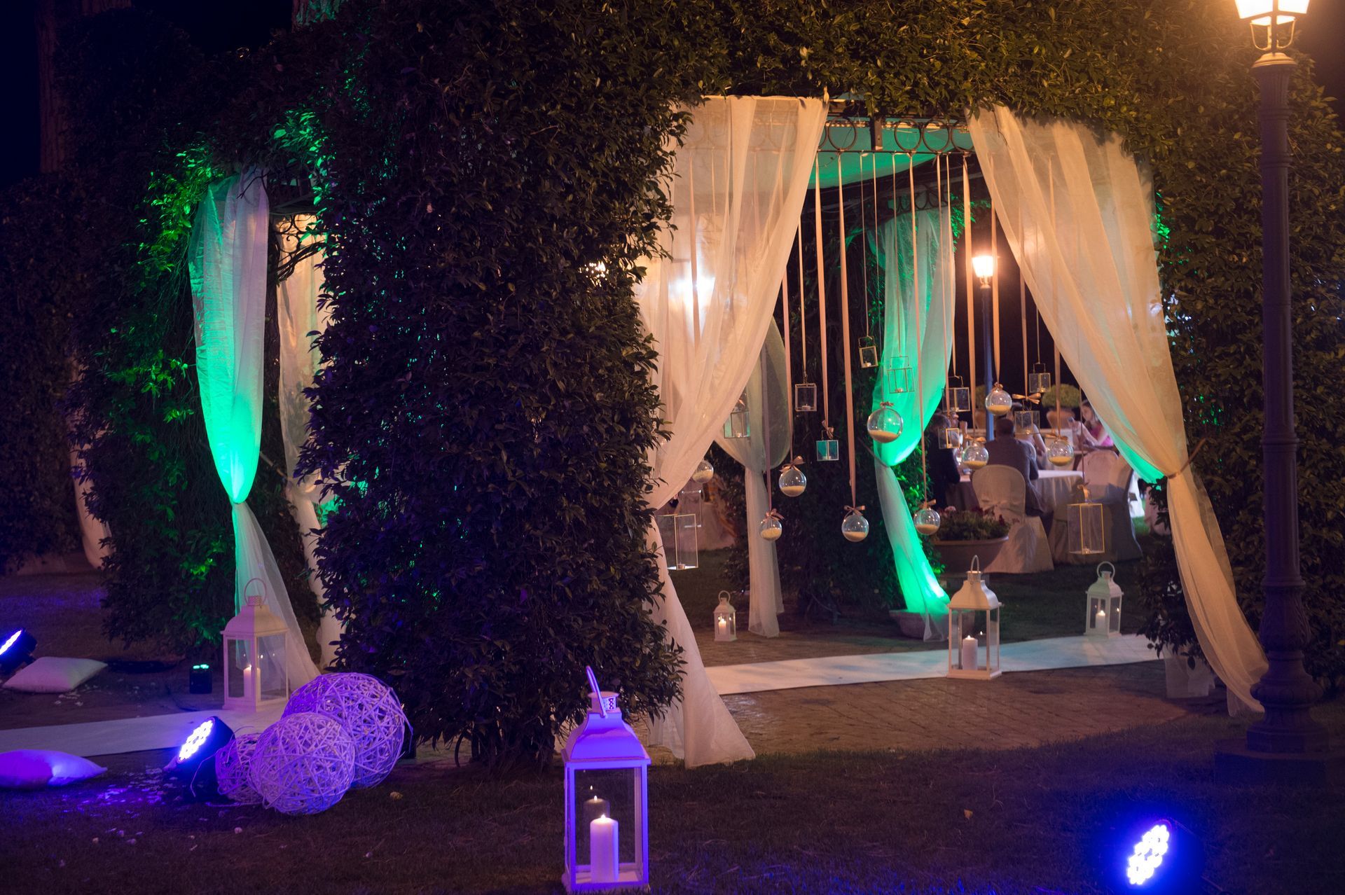 Un gazebo è illuminato con luci verdi e tende bianche