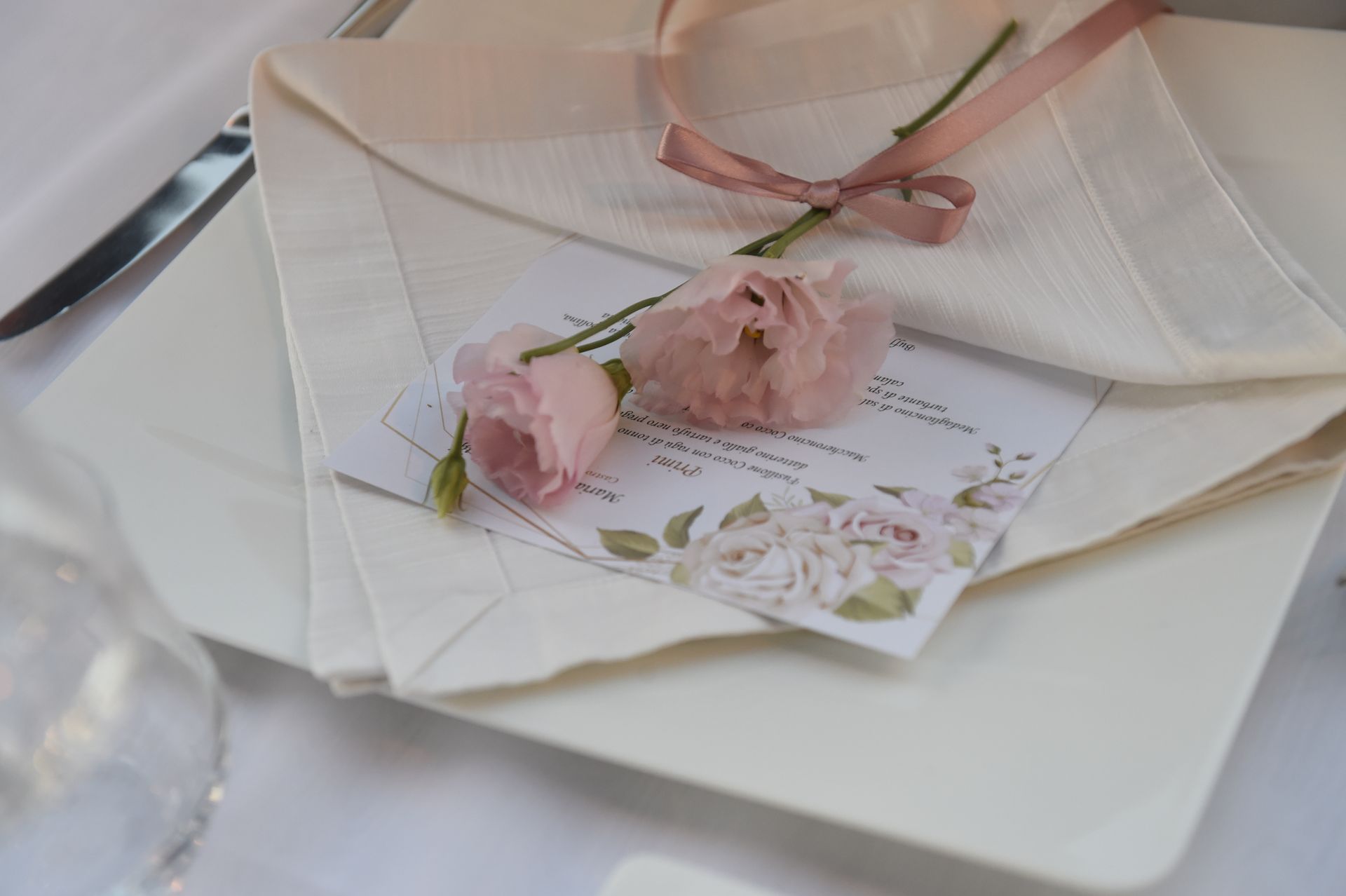 Un piatto bianco con un tovagliolo e dei fiori sopra.