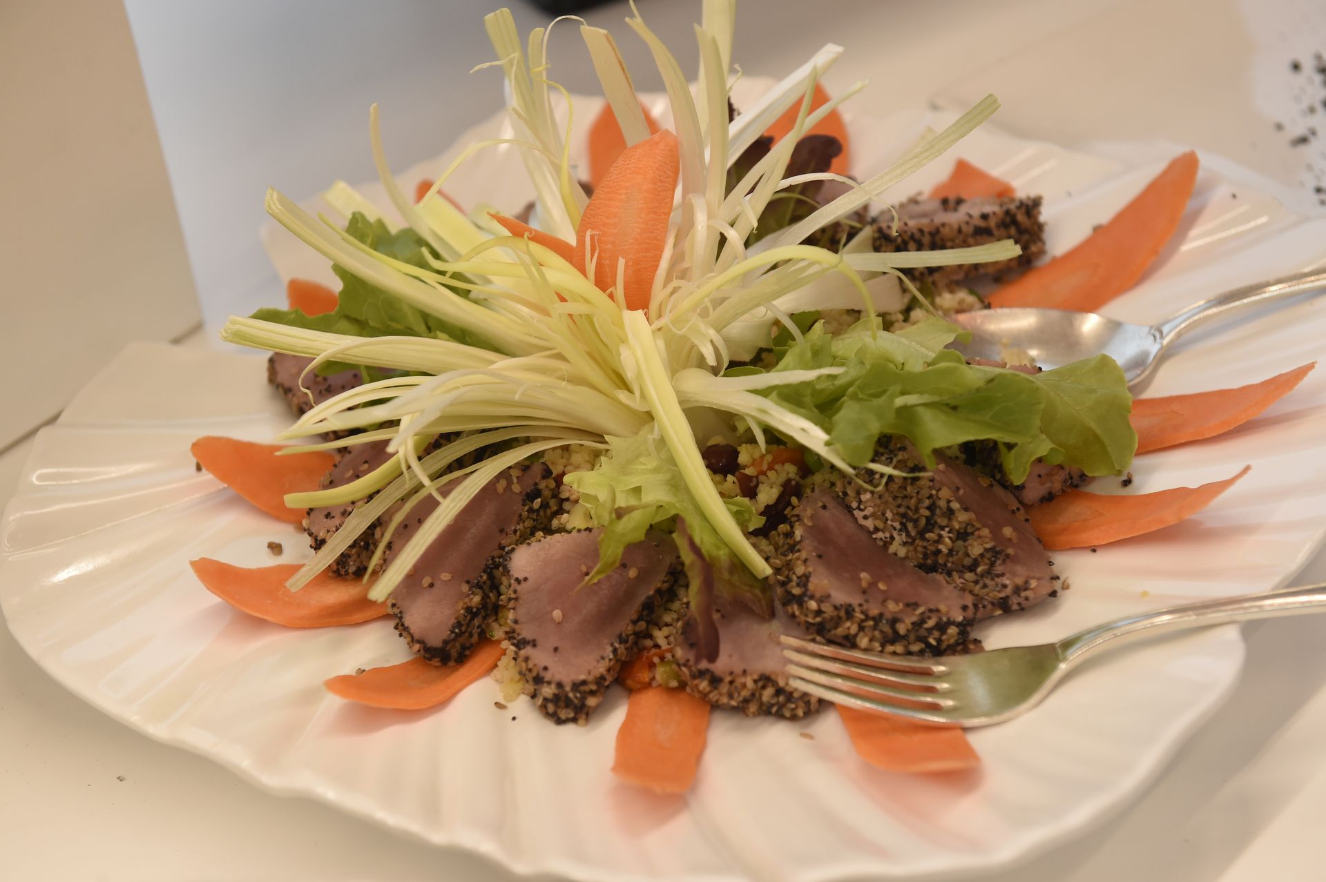 Un piatto bianco condito con carne e verdure con una forchetta