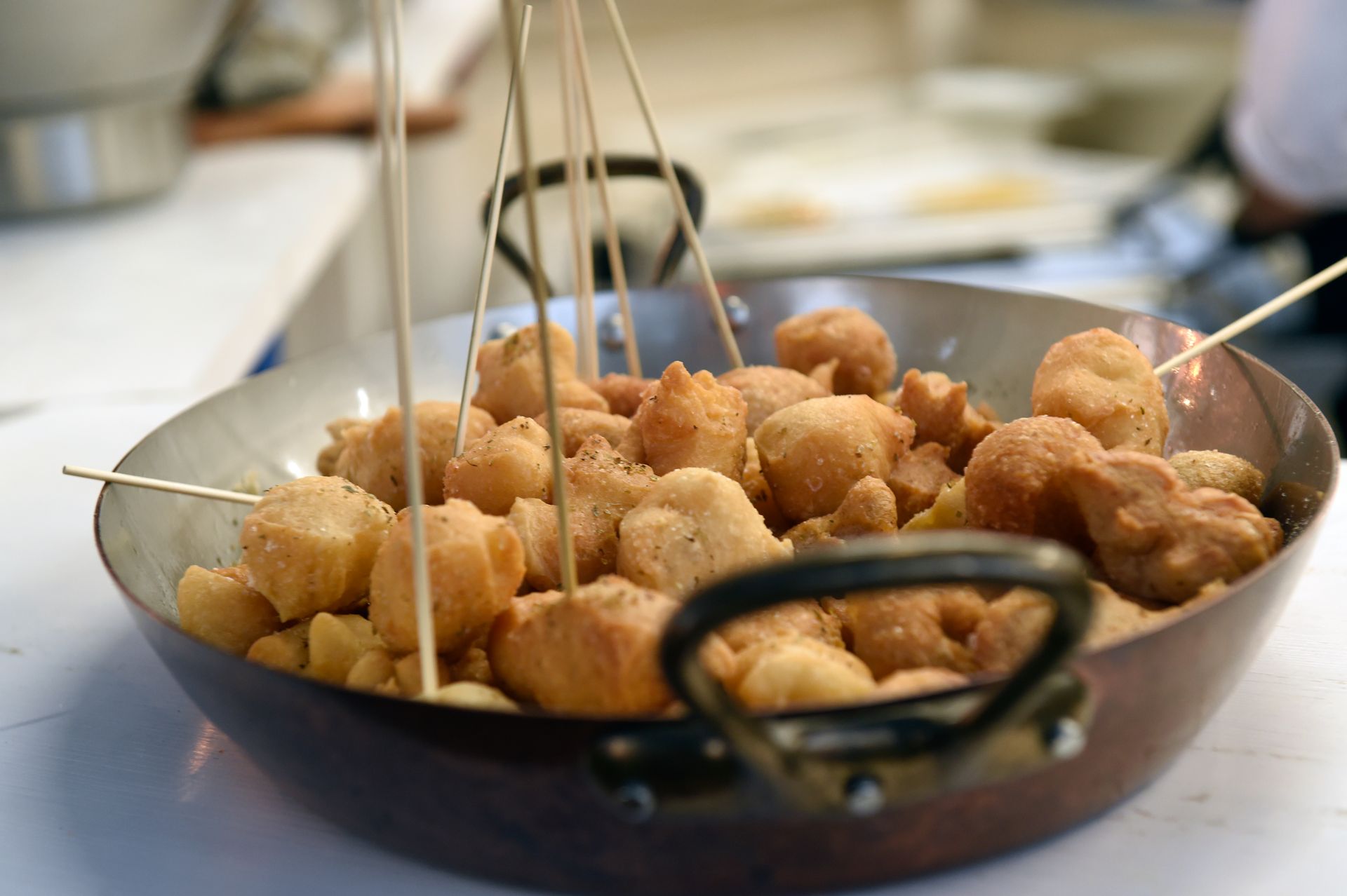 Una padella piena di cibo fritto da cui spuntano dei bastoncini