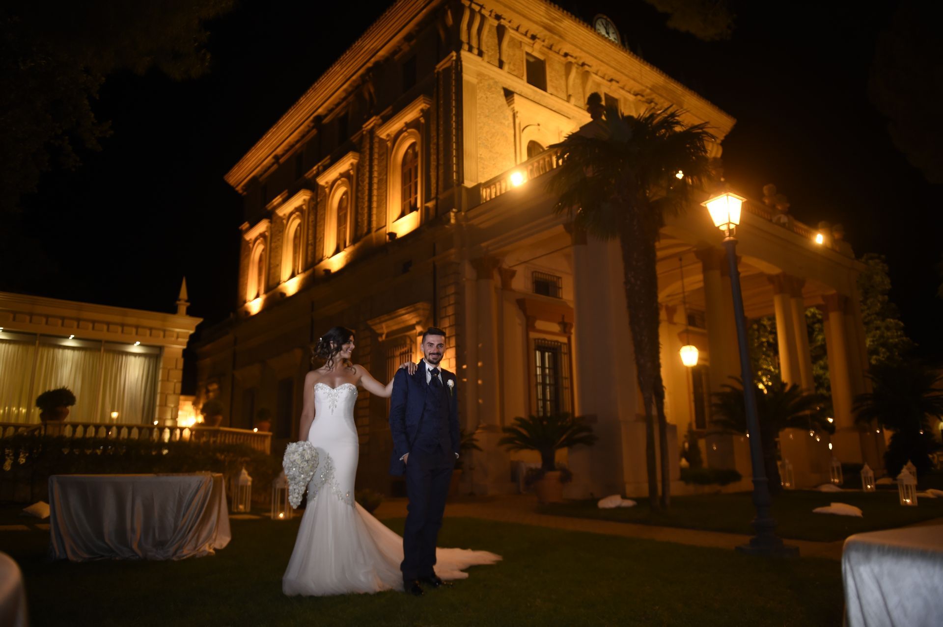 Una sposa e uno sposo sono in piedi davanti a un grande edificio di notte.