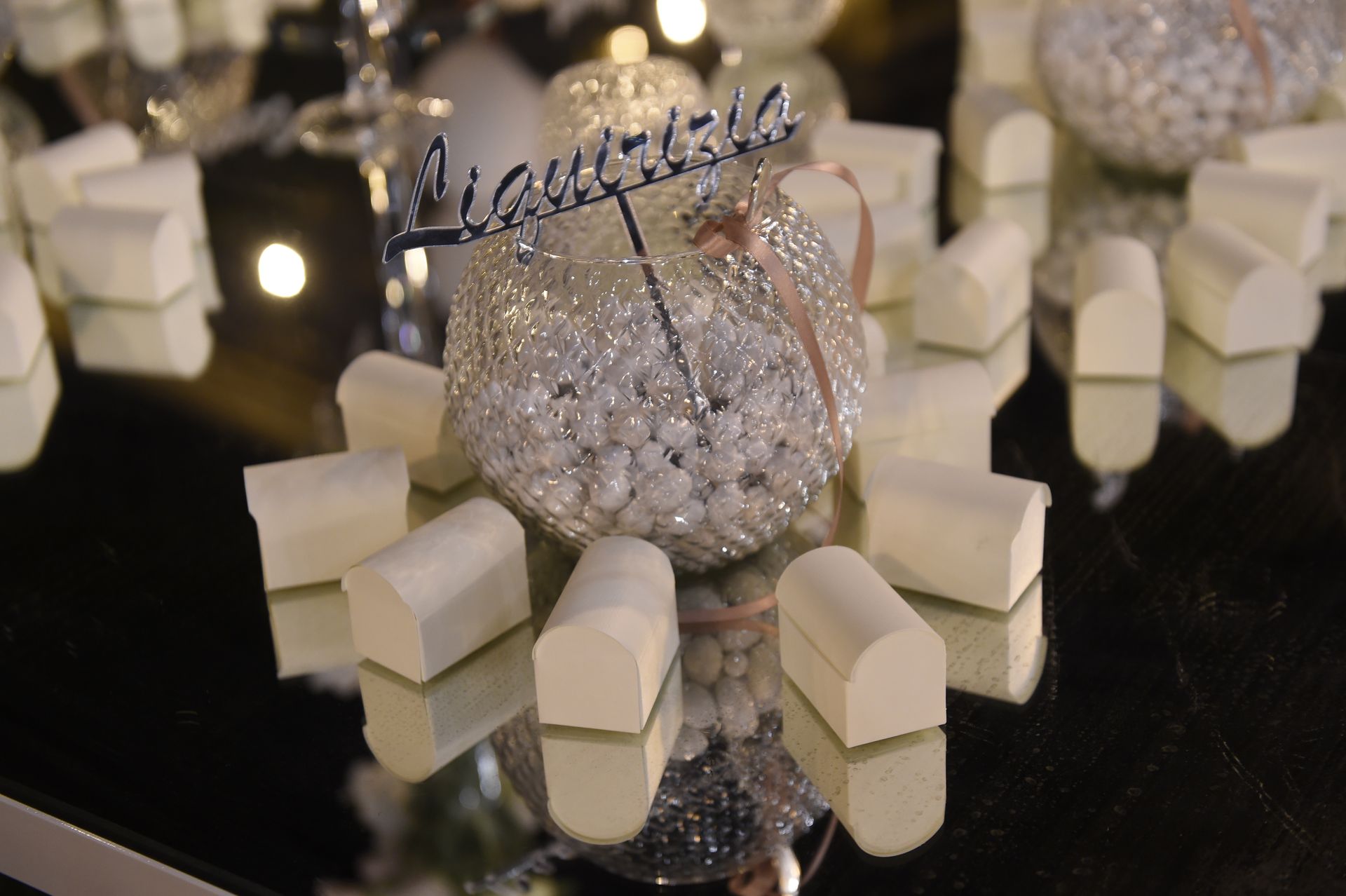 Su un tavolo c'è un contenitore di vetro pieno di caramelle bianche.