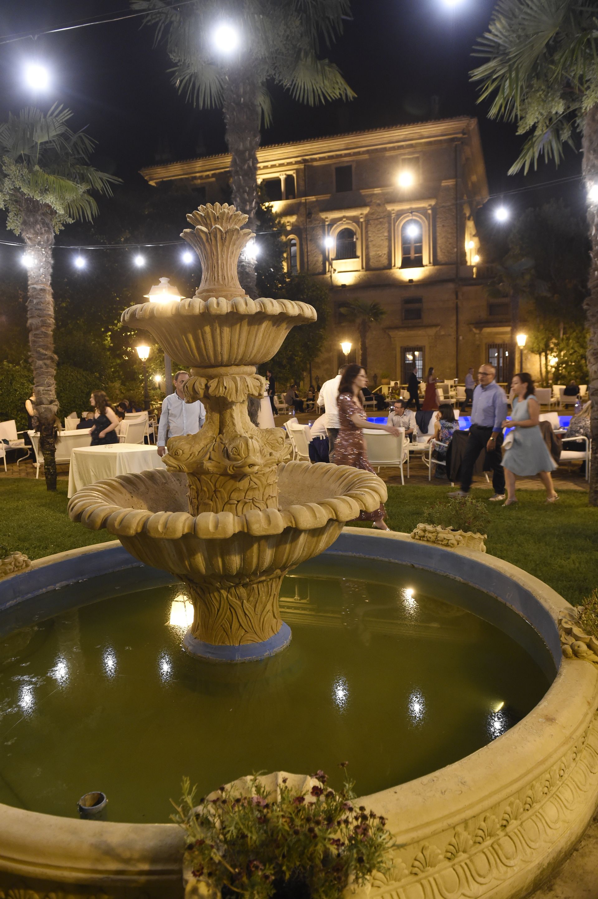 Di notte davanti ad un edificio viene illuminata una fontana.
