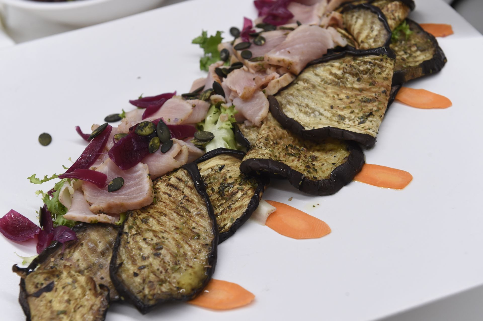 Un piatto bianco condito con verdure e carne affettate