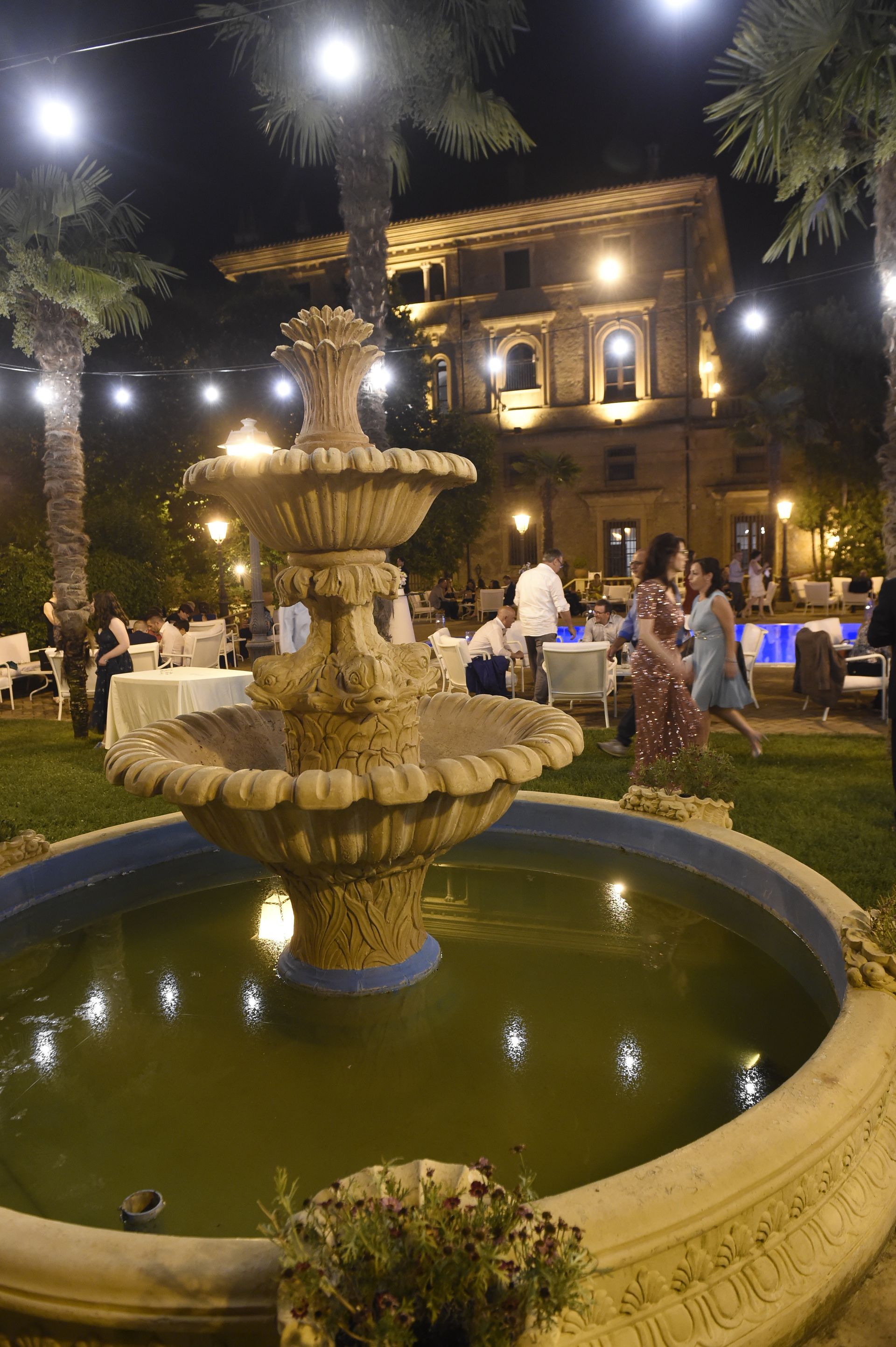 Un gruppo di persone sta di notte attorno ad una fontana.