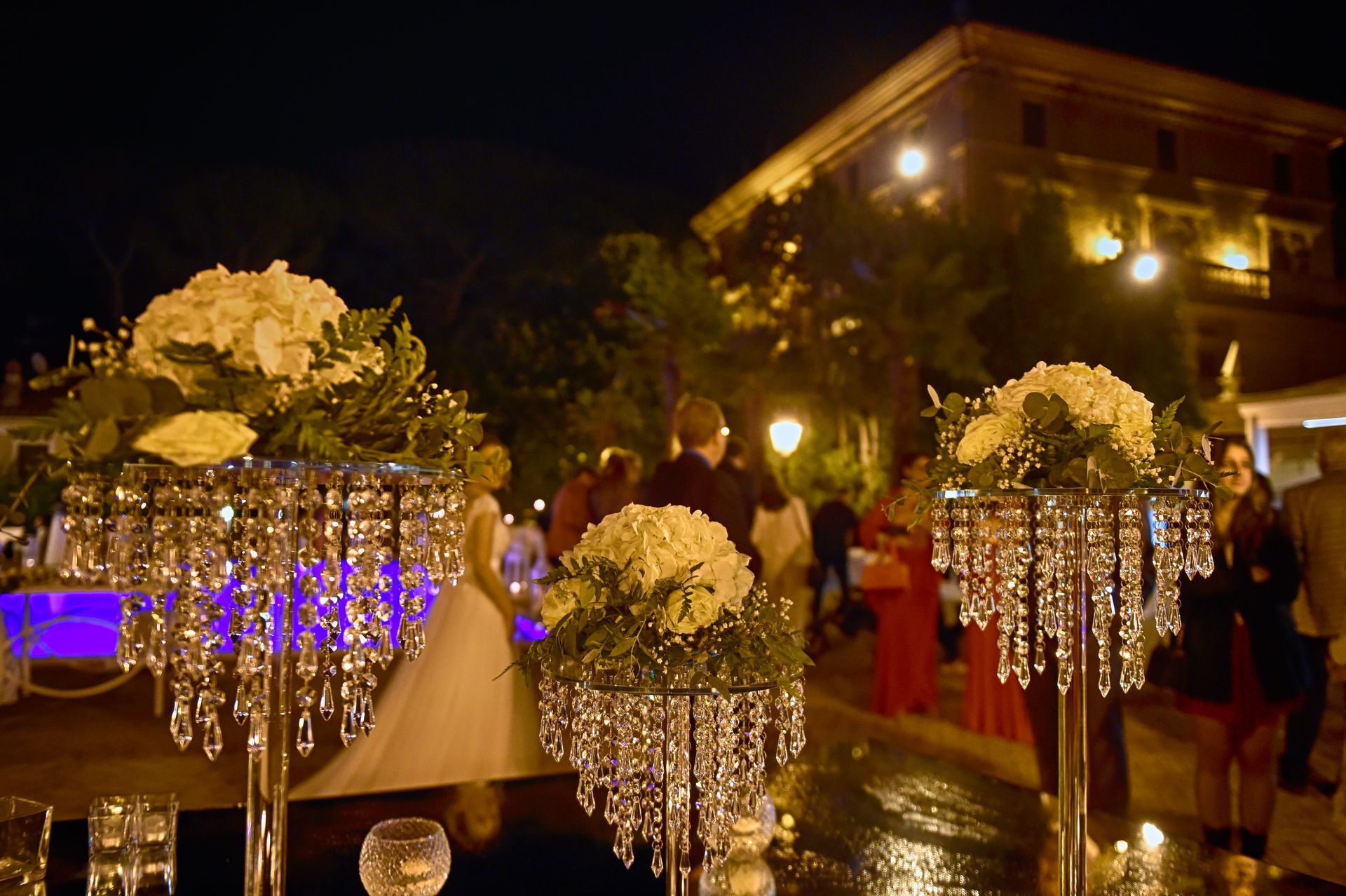 Gli sposi sono in piedi davanti a un tavolo decorato con fiori e cristalli.