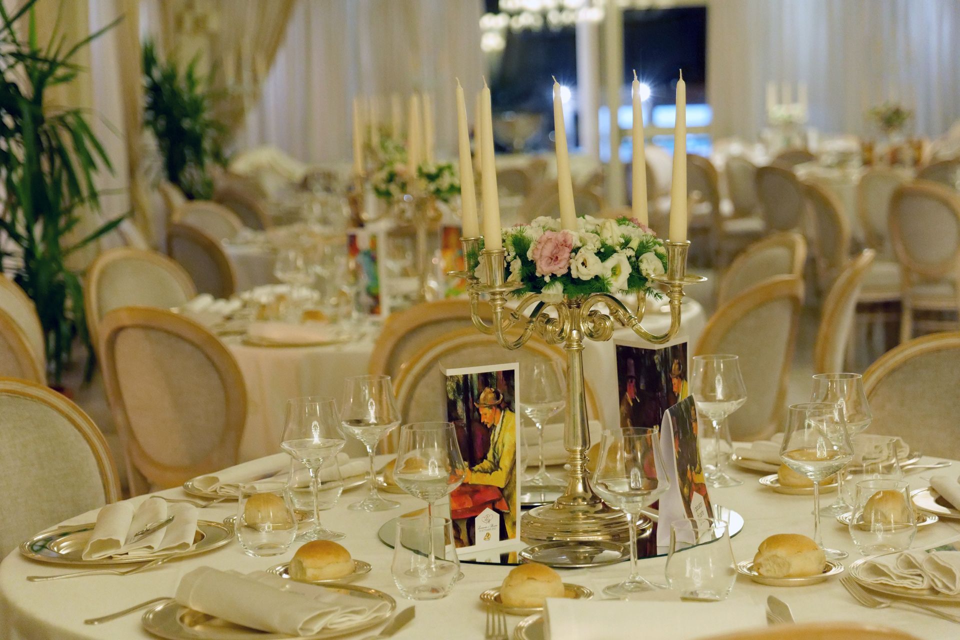 Una tavola apparecchiata per un ricevimento di nozze con candele e fiori sopra.