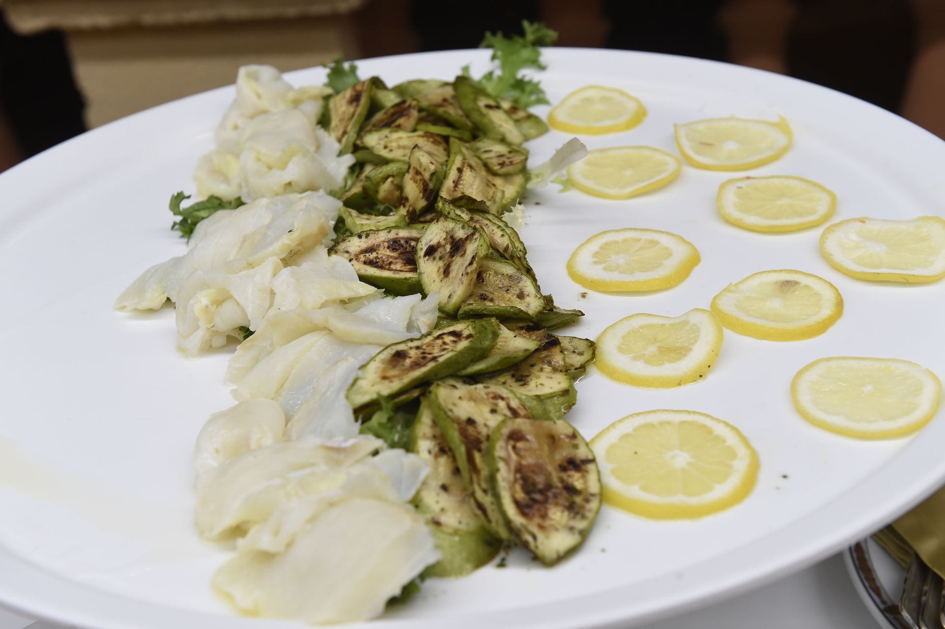 Un piatto bianco condito con verdure grigliate e fette di limone.