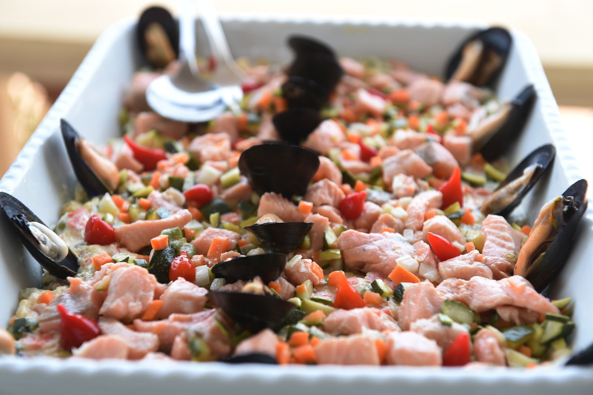 Una casseruola bianca piena di frutti di mare e verdure