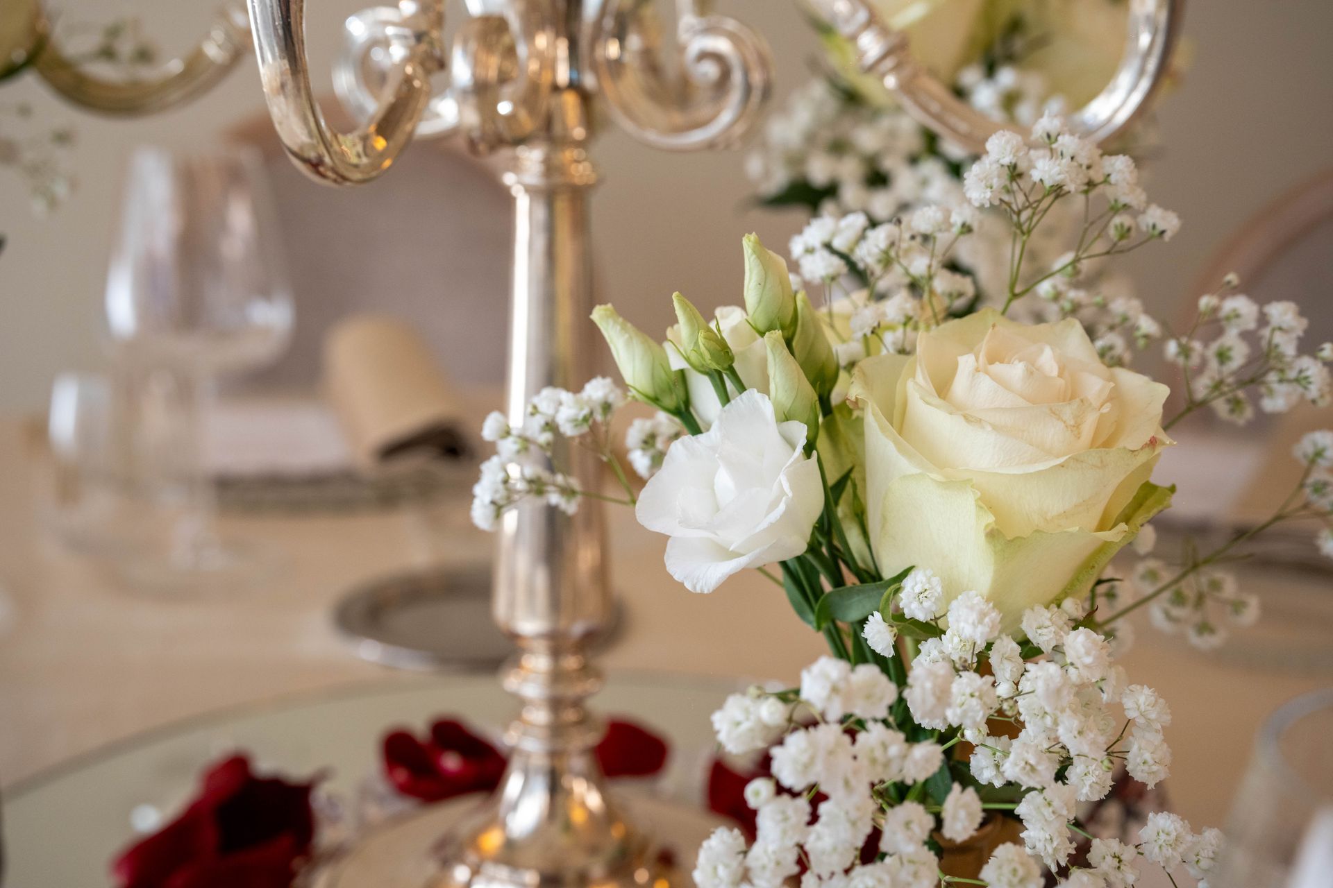 Un candelabro con rose bianche e gypsophila su un tavolo.
