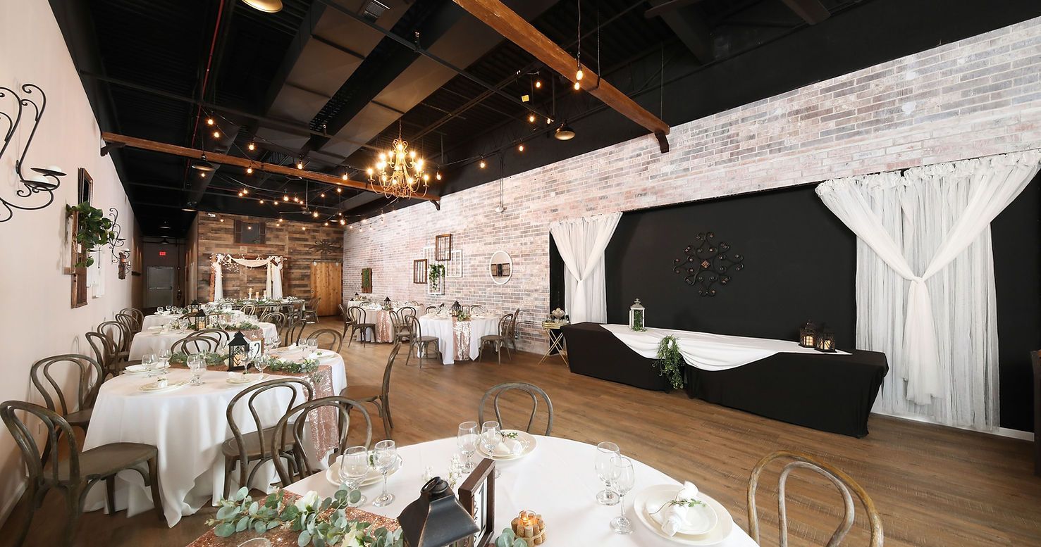 A large room with tables and chairs set up for a wedding reception.
