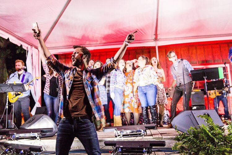 A man is standing on a stage with his arms in the air.