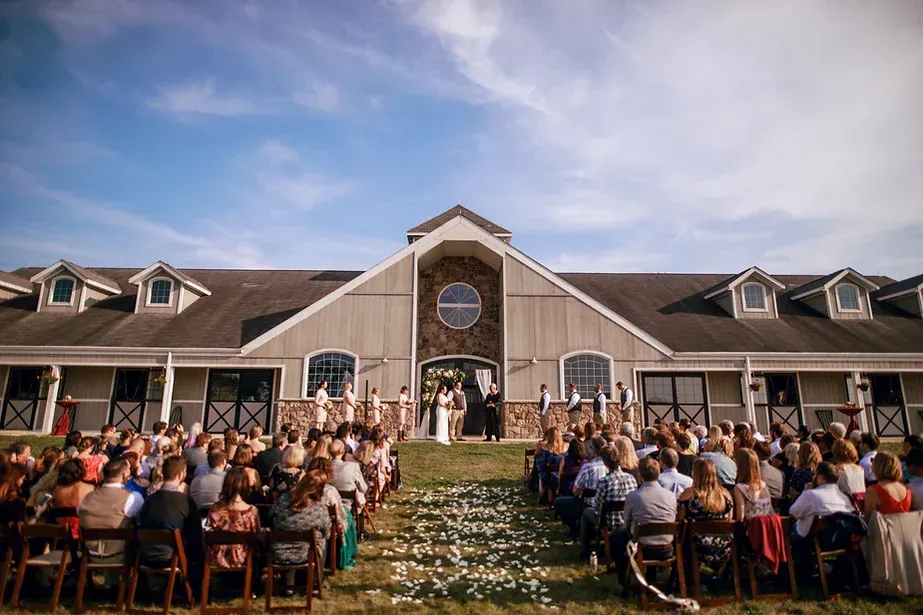 A large group of people are sitting in front of a large building watching a wedding ceremony.