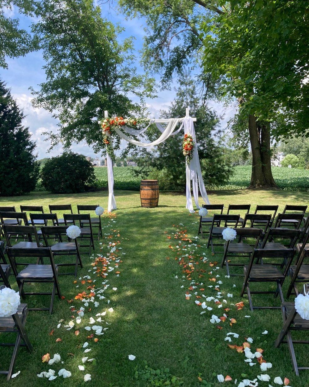 A row of folding chairs are lined up in a grassy field for a wedding ceremony.