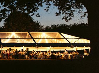 A group of people are sitting under a clear tent at night