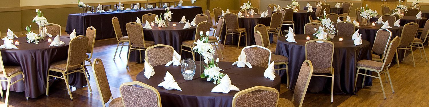 A large room with tables and chairs set up for a wedding reception.