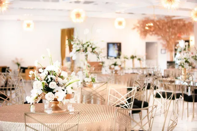 A large room with tables and chairs and a vase of flowers on a table.