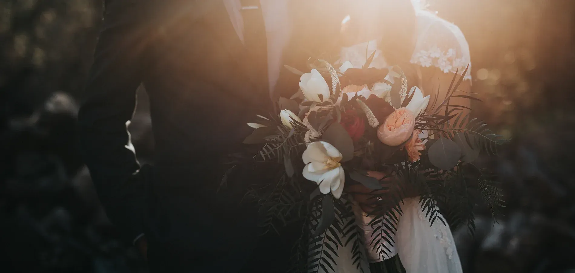 A bride and groom are holding a bouquet of flowers.