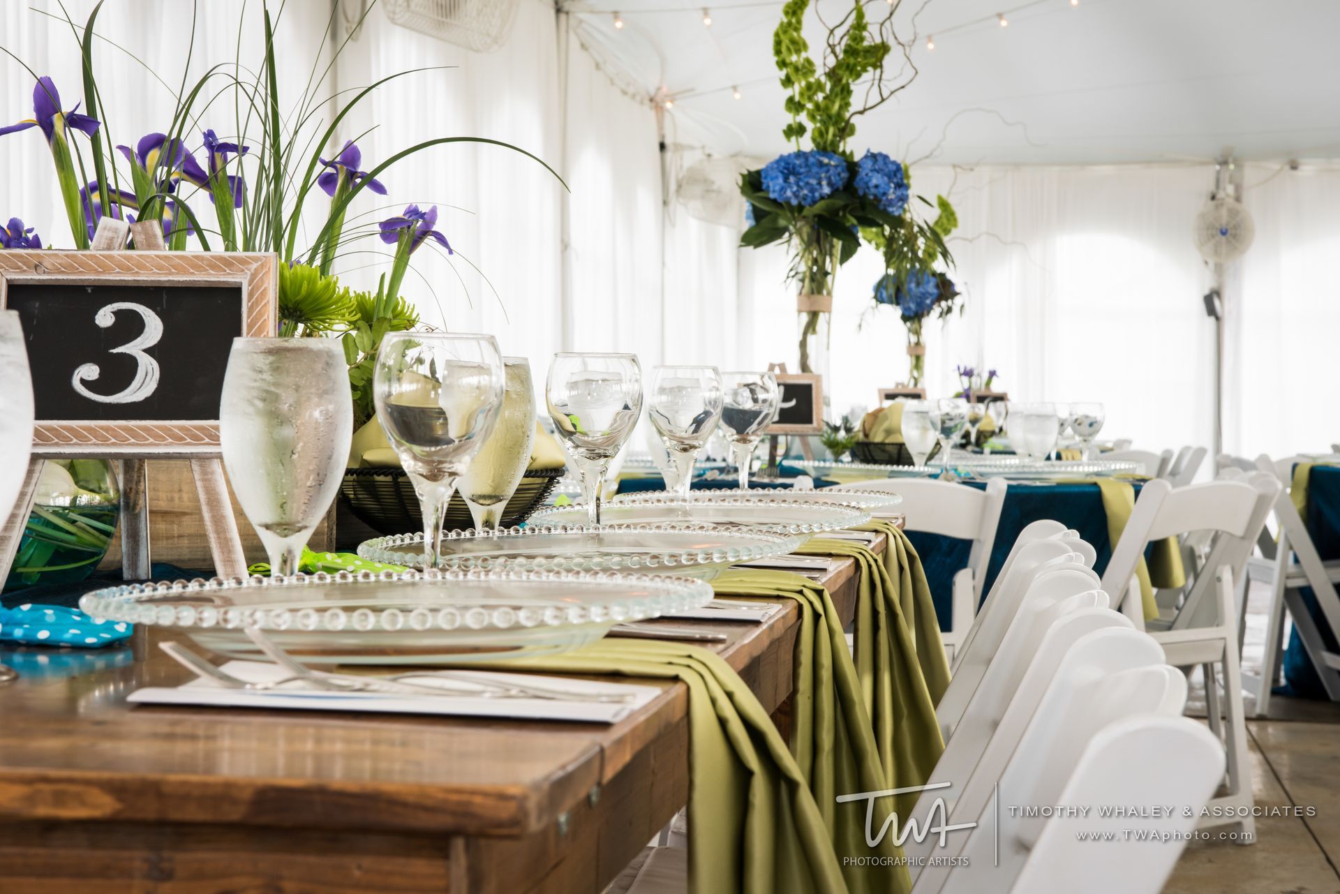 A table set for a wedding reception with plates , glasses , and flowers.
