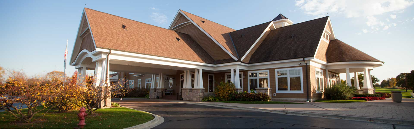 A large house with a brown roof is sitting on top of a lush green field.