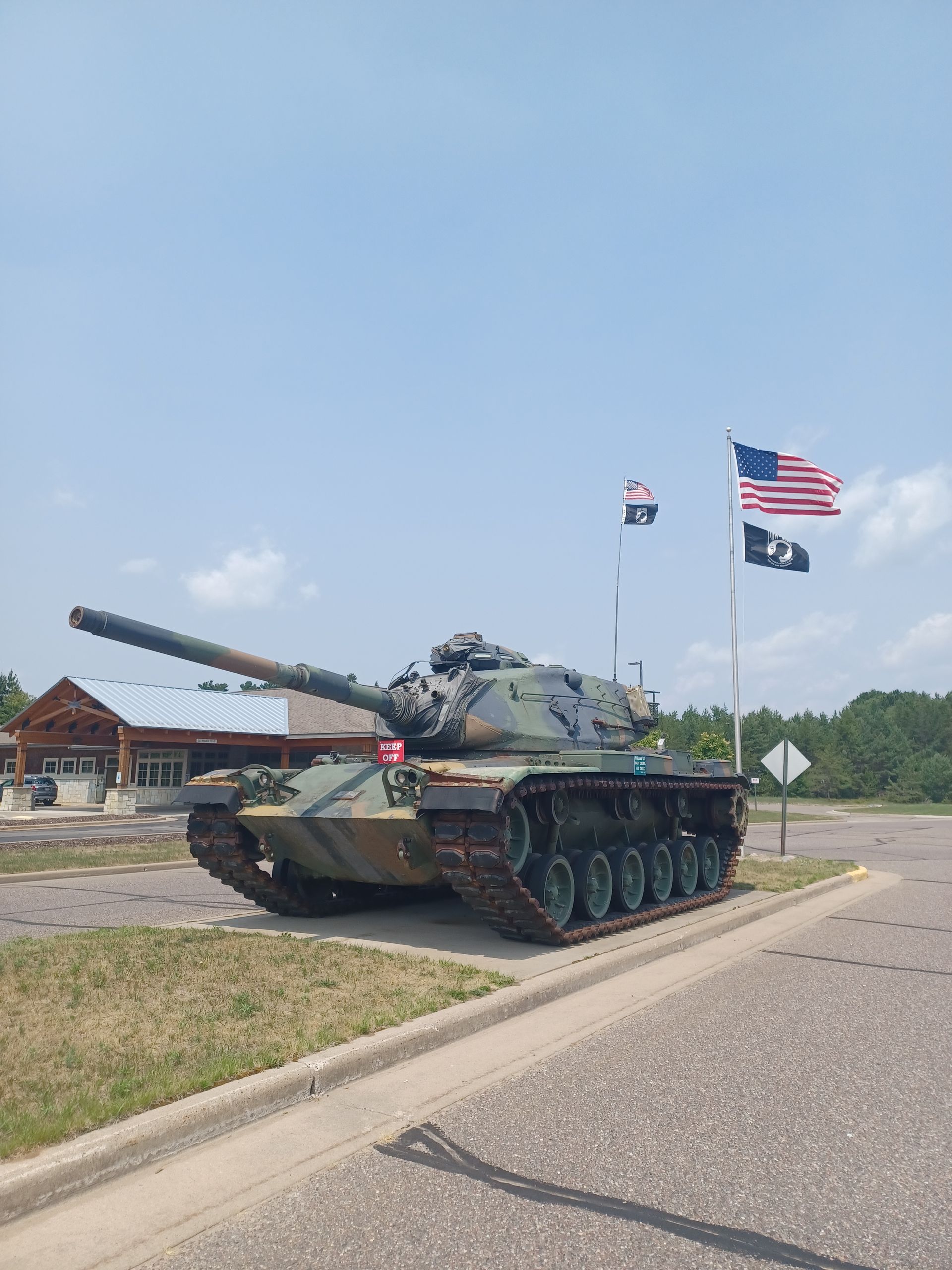 A tank is parked on the side of the road next to a building.