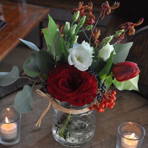 A vase filled with flowers and candles on a table