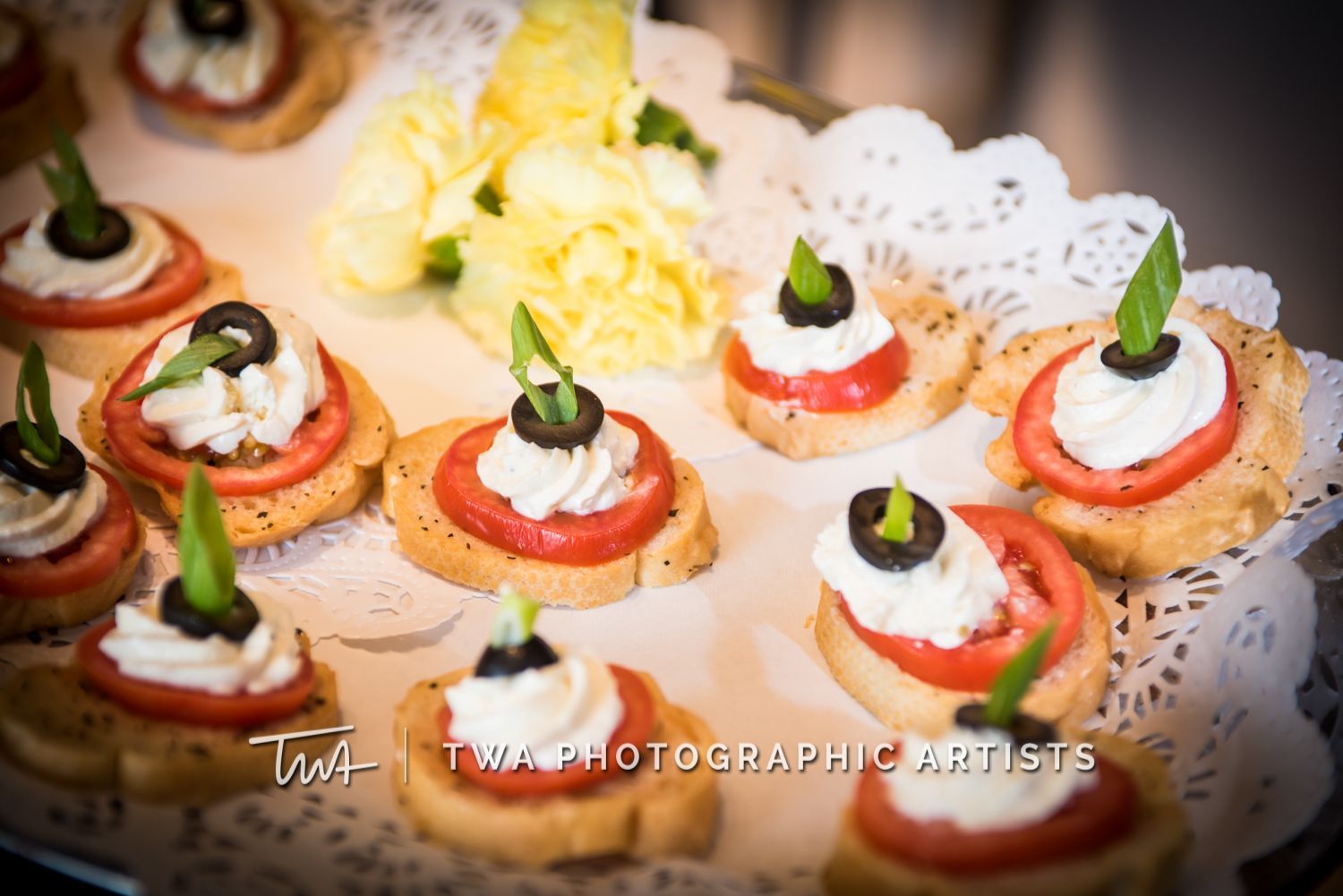 A plate of food with tomatoes , olives , and whipped cream on it.