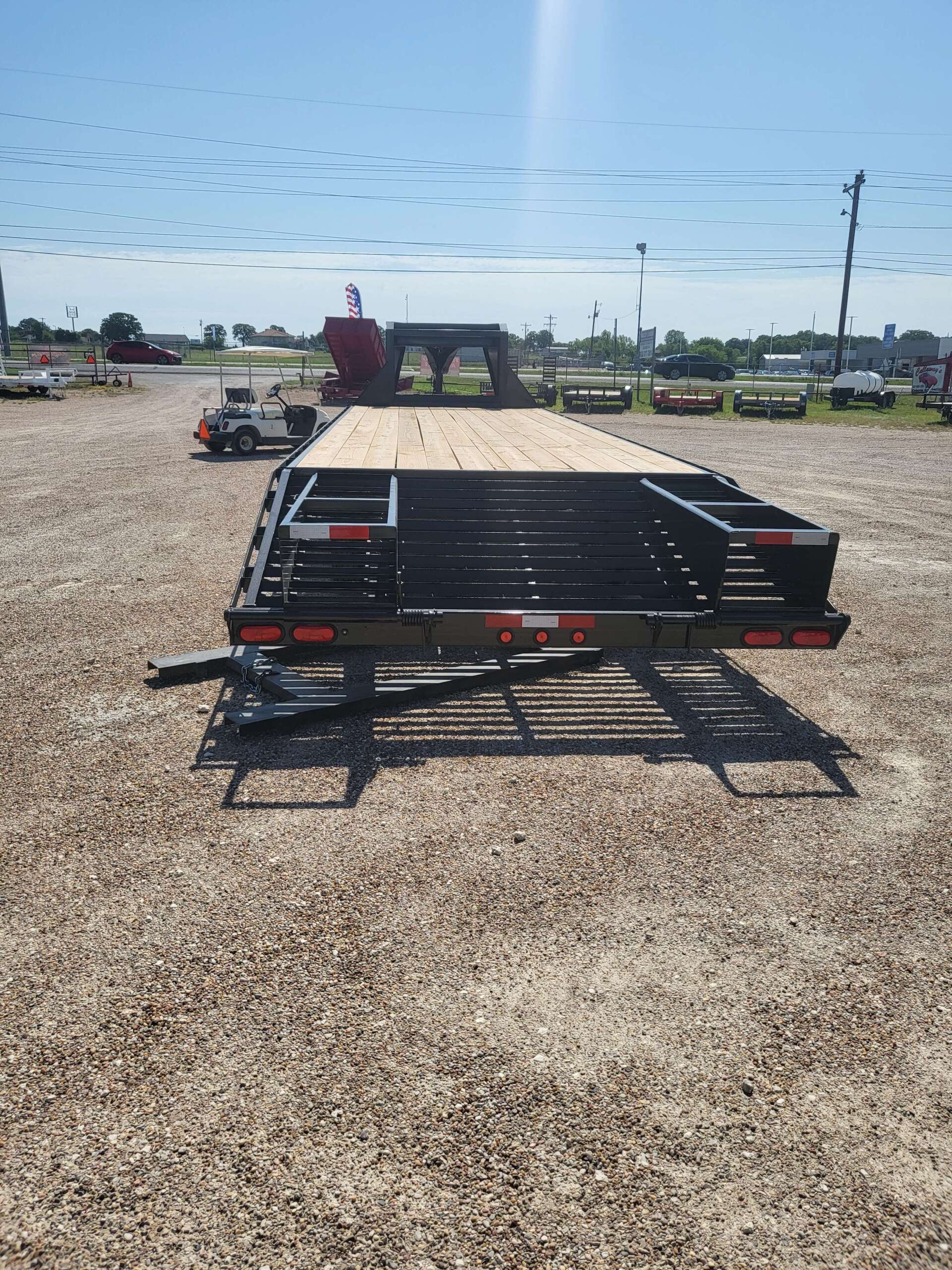A flatbed trailer is parked in a gravel lot.