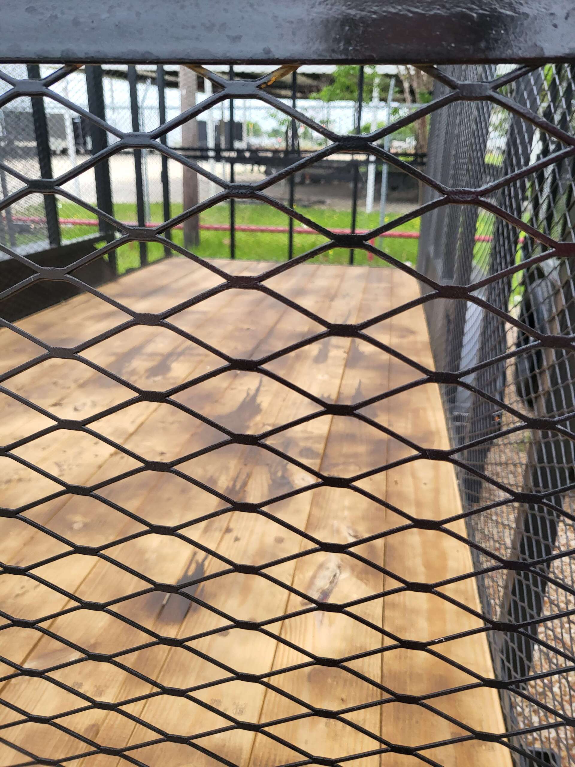 A wooden table is behind a metal mesh fence