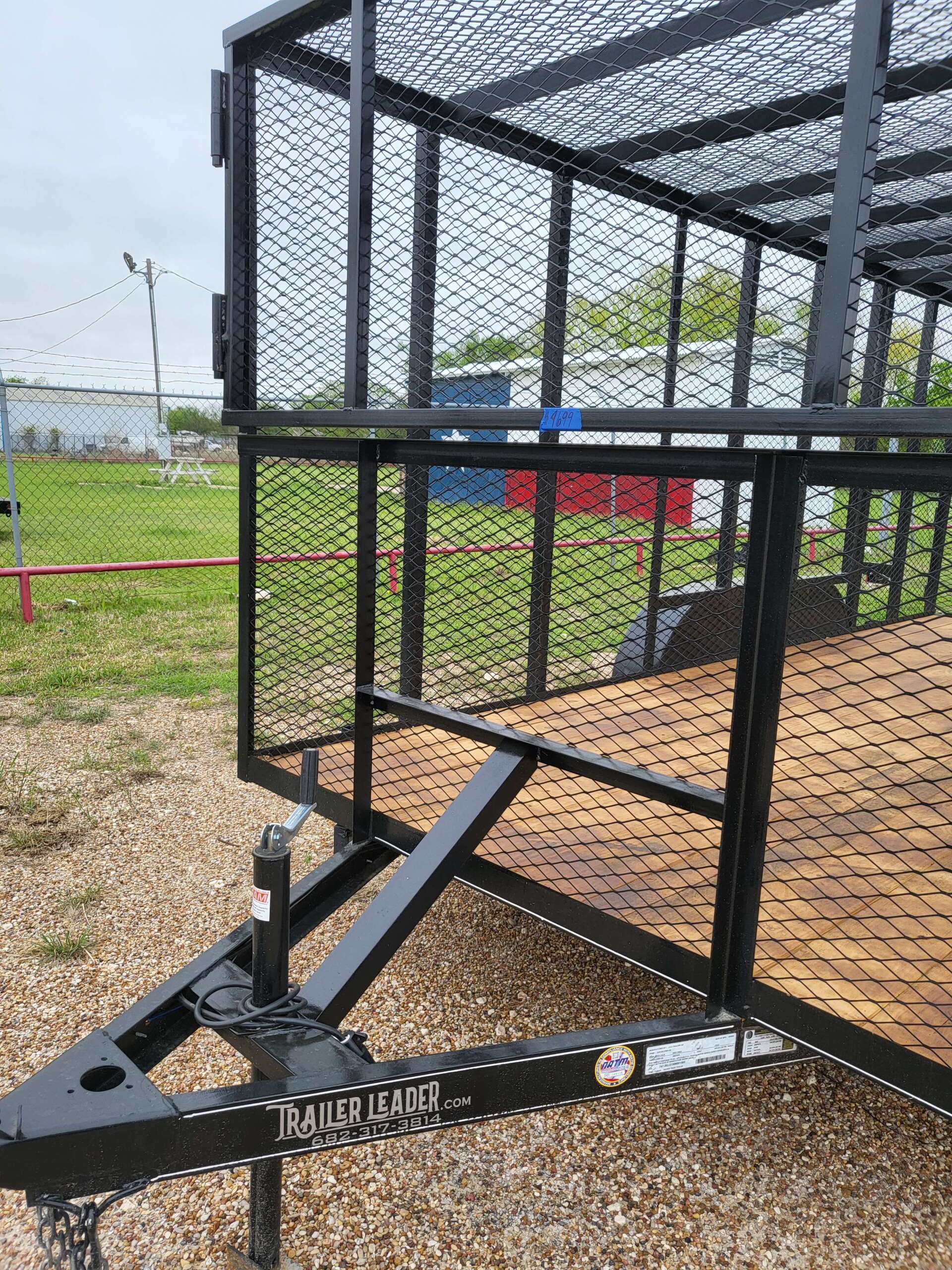 A trailer with a cage on top of it is parked in a field.